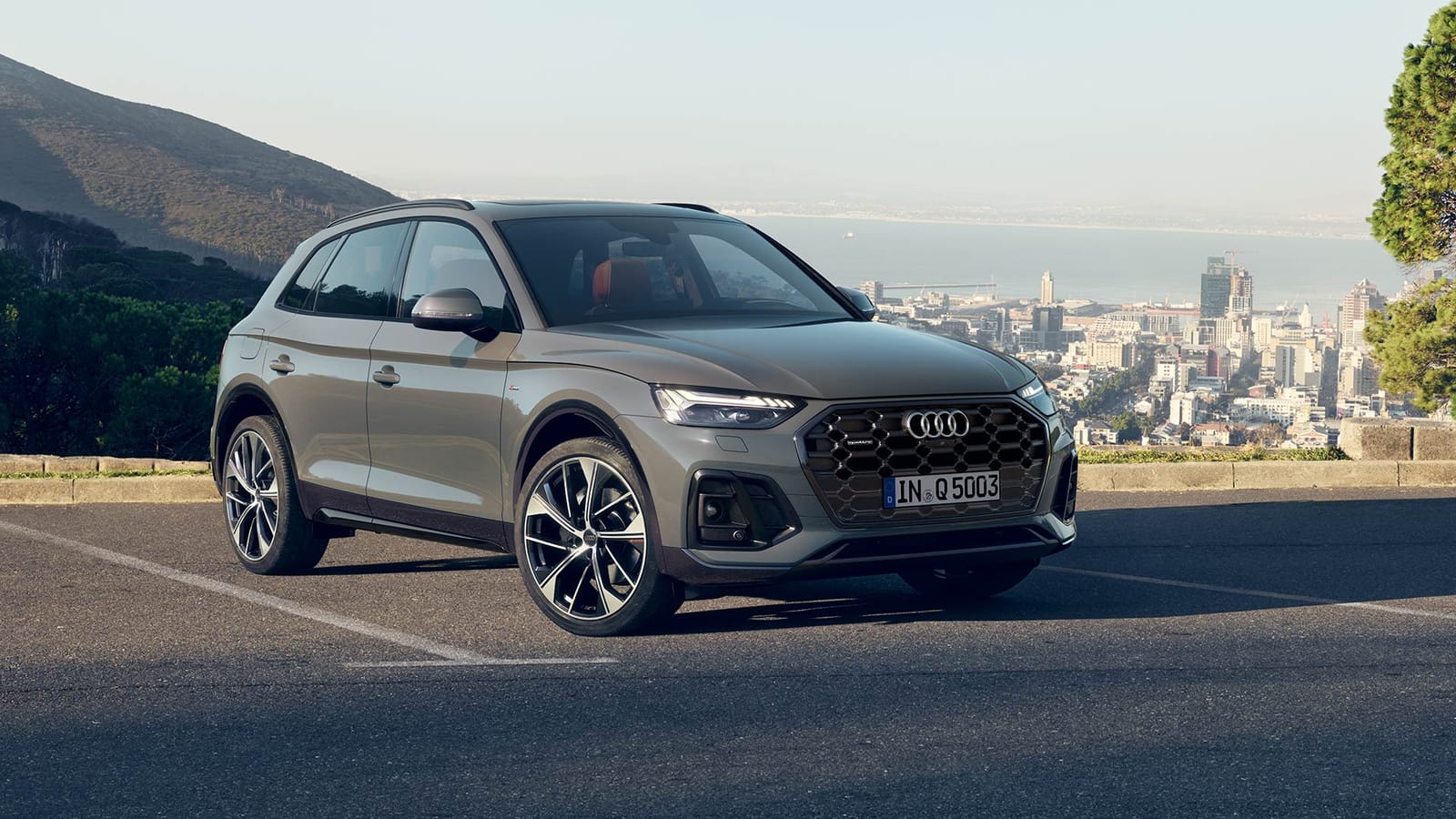 Grey Audi Q5 SUV parked at a hilltop lookout above a coastal city