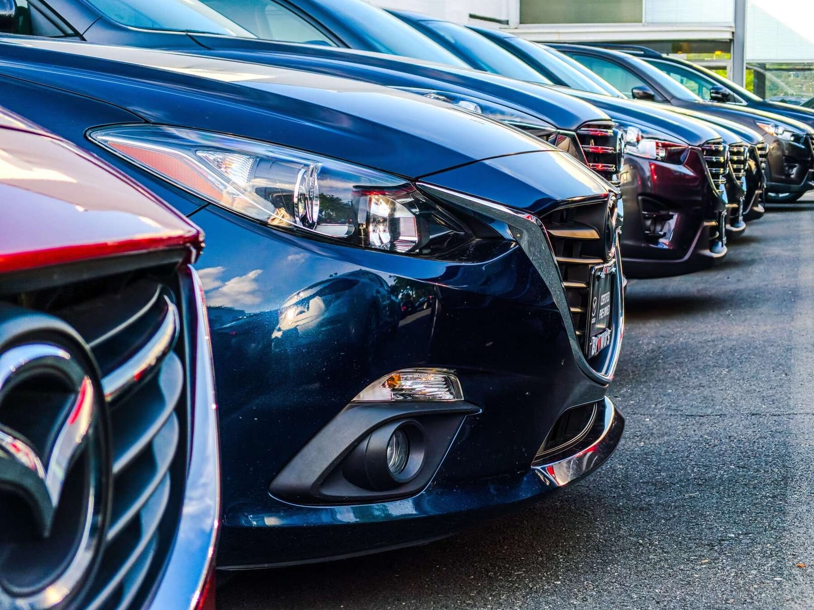 Row of Mazda cars lined up nose-first in a car park