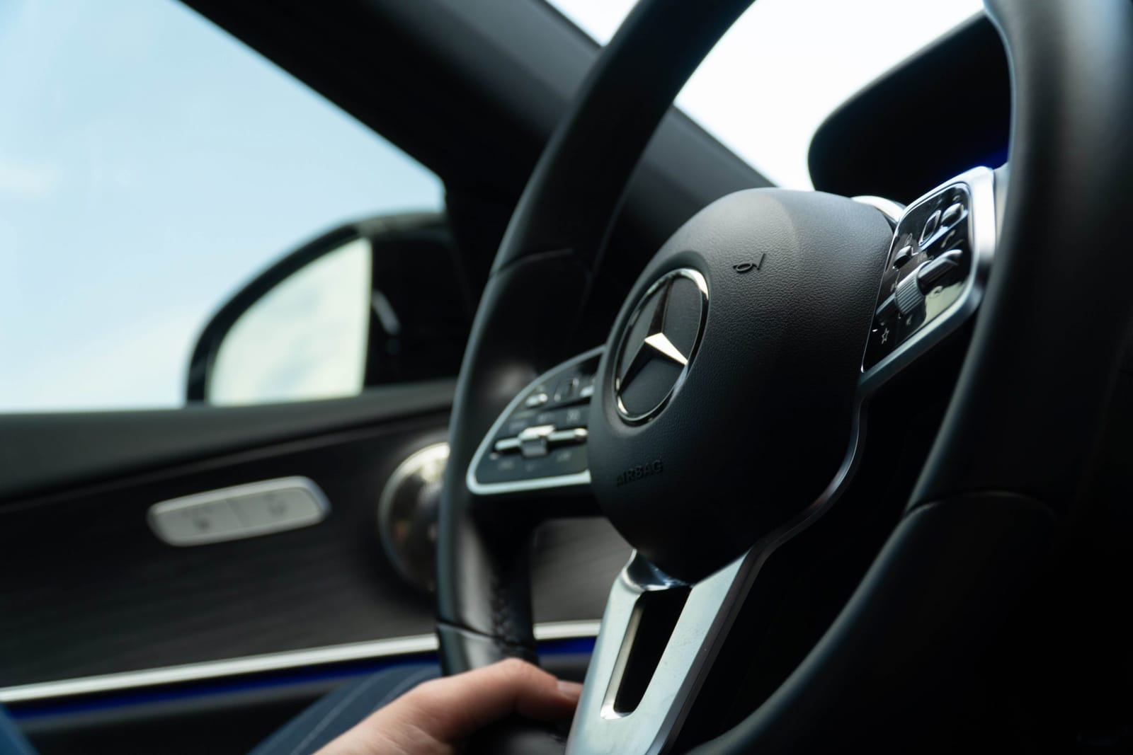 Driver holding the steering wheel of a Mercedes-Benz with the door open